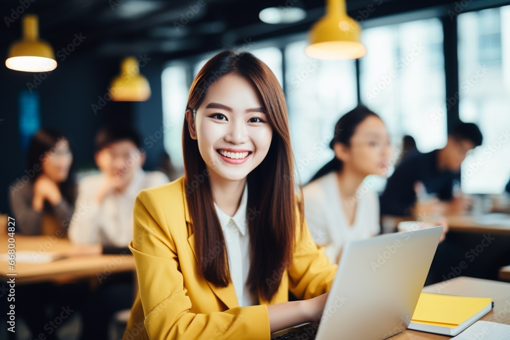 Portrait of young woman working on laptop computer in modern office, Confident employee smiling happily while working with coworkers. Portrait of young woman working on laptop computer in modern office, Confident employee smiling happily while working with coworkers.