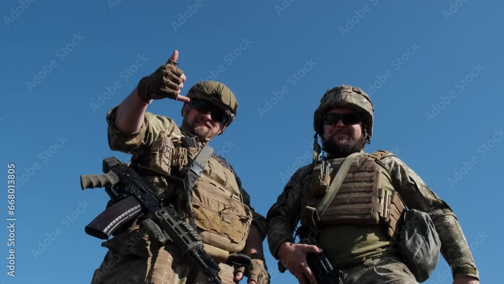 Military men in camouflage uniforms against a blue sky. The concept of victory and positive emotions during combat. Military men in camouflage uniforms against a blue sky. The concept of victory and positive emotions during combat.