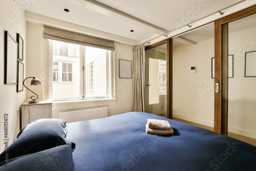 a bedroom with a bed  mirror and closet space in the photo is taken from the window to the other room