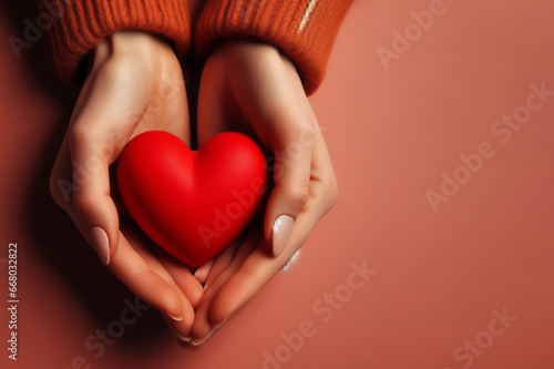 hands hold a red heart on a orange background photo