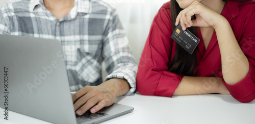 E-commerce Concept. Happy couple holding credit card enjoying doing online shopping and using laptop enter their card number in-app to purchase and payment in internet store