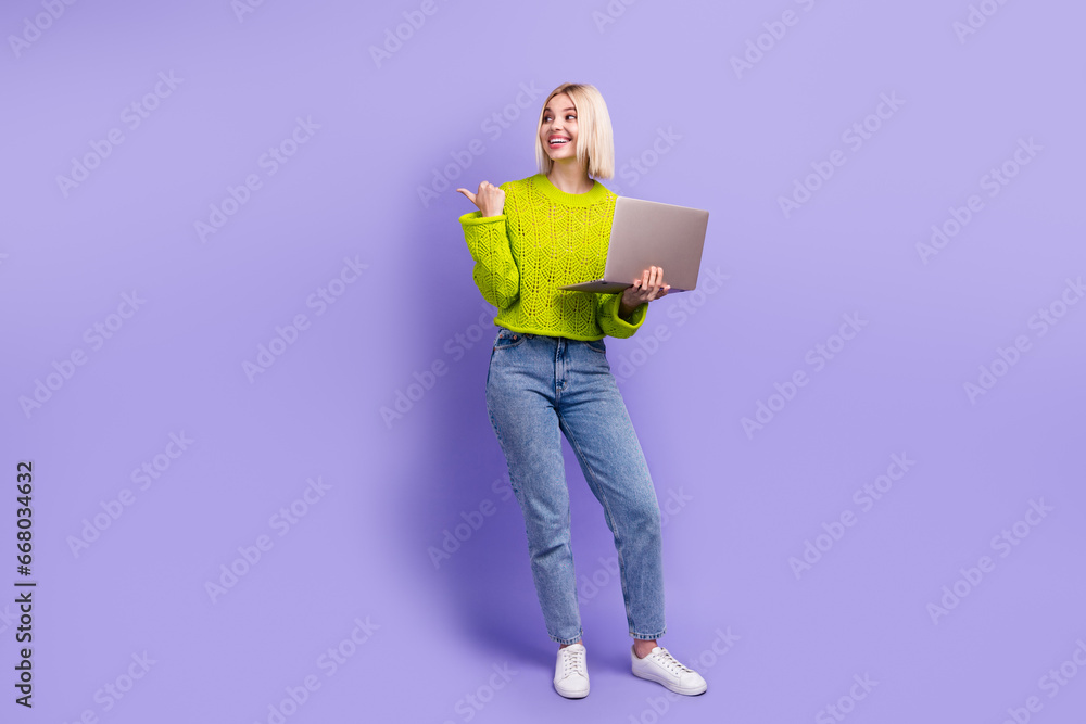 Full length photo of cheerful dreamy woman dressed knitted sweater studying device thumb empty space isolated violet color background Full length photo of cheerful dreamy woman dressed knitted sweater studying device thumb empty space isolated violet color background