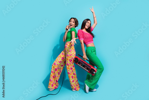 Full body photo of two pretty girls concert beautiful famous celebrity singing microphone sound boombox isolated on blue color background photo