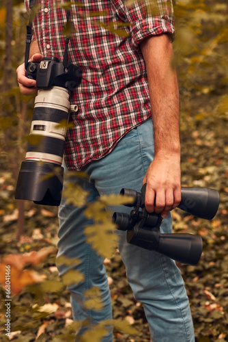 Man using binoculars and camera for birdwatching and other observing animals in nature.