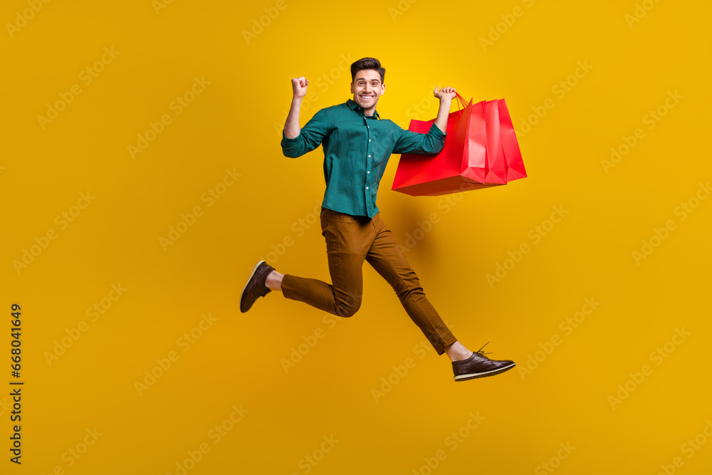 Photo of cheerful crazy man wear trendy clothes running empty space showing fist hand isolated on yellow color background