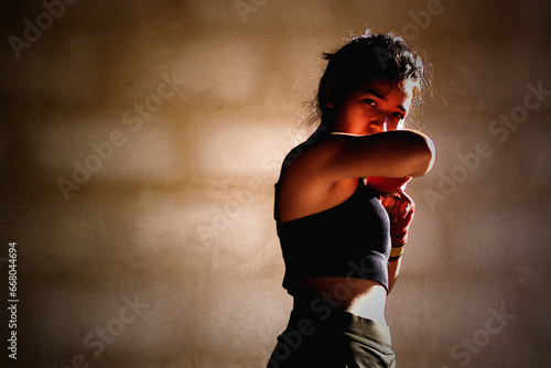 Young woman practicing boxing at the gym, she wears boxing gloves. © Subhakitnibhat