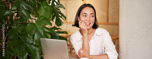 Stylish young freelancer, businesswoman sitting in cafe with laptop and working, drinking coffee photo