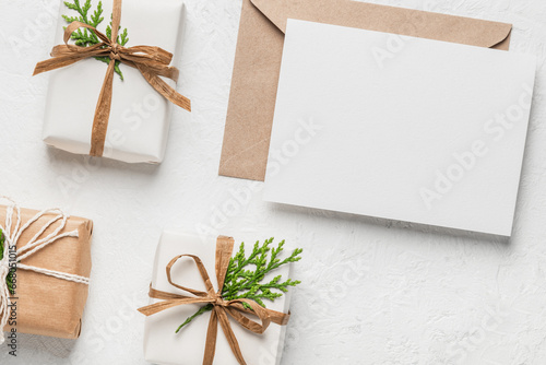 Christmas gift boxes in eco packaging, kraft paper envelope, blank card and thuja branches. Christmas or holiday card. Boxing Day.