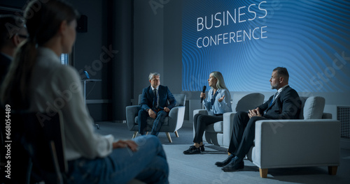 International Business Conference: Caucasian Female Tech CEO Talking With Male Host In Front Of Audience Of Diverse Attendees. Successful Woman Delivering Inspirational Speech For Women In Leadership. photo