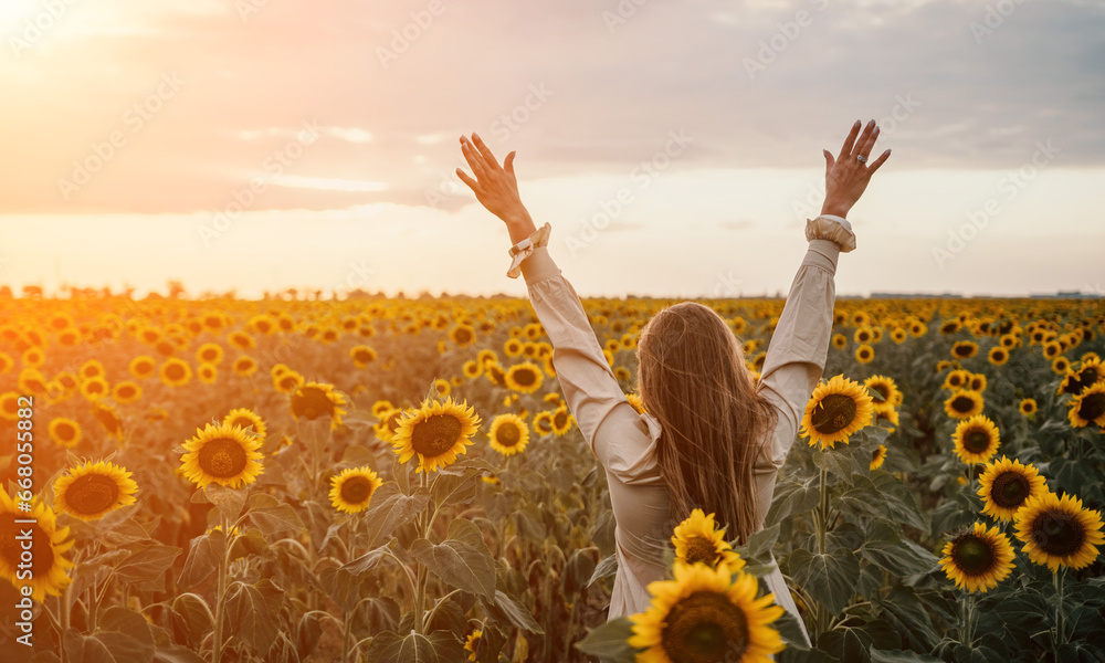 Woman in Sunflower Field: Happy girl in a straw hat posing in a vast field of sunflowers at sunset, enjoy taking picture outdoors for memories. Summer time. - obrazy, fototapety, plakaty 