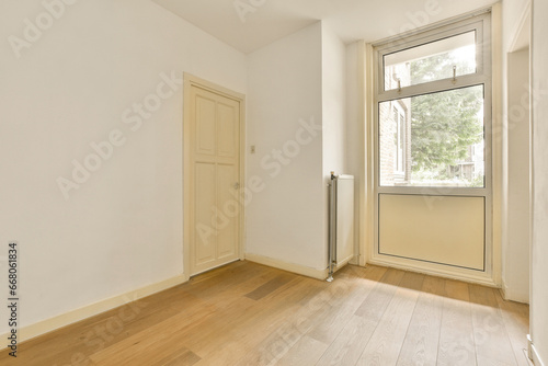 an empty room with wood floors and white walls  there is a door leading to the left side of the room