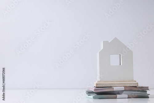 Cash money and wooden house on white background, space for text