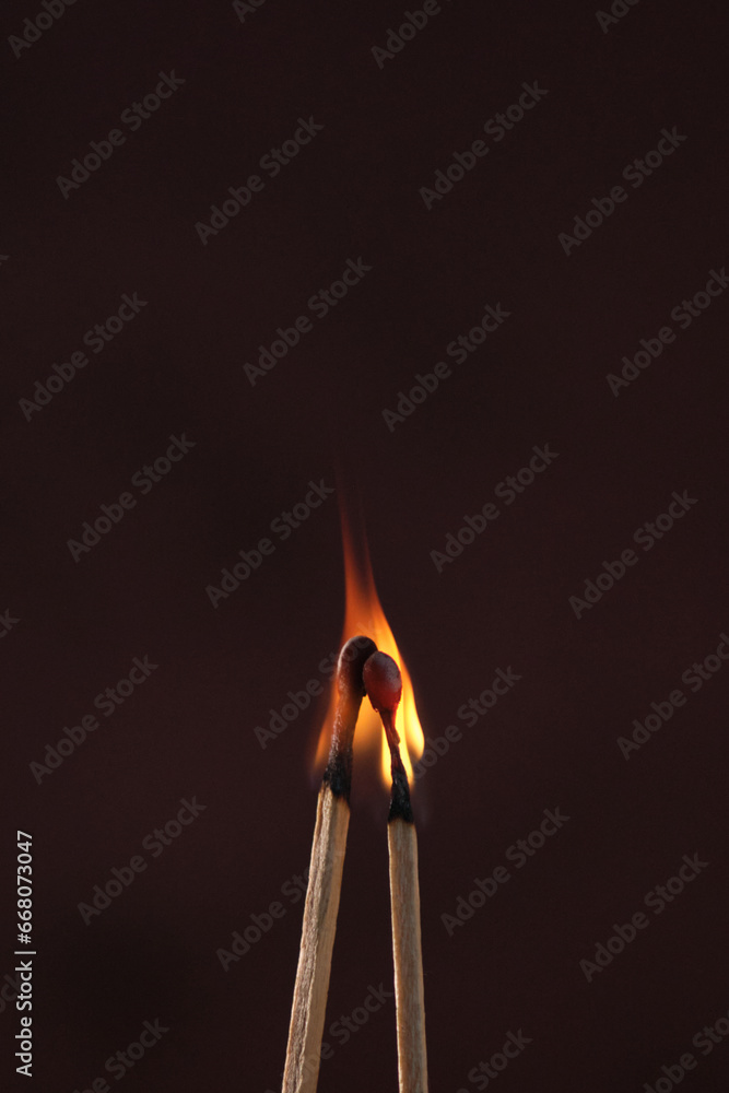 two lighted matches on a dark background two lighted matches on a dark background