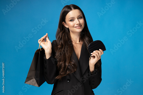 Girl with purse and shopping bags on blue background.