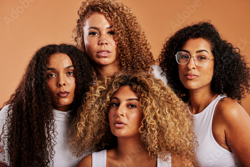 Diverse women in white shirts posing together against an orange background photo