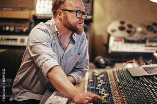 Music producer working on a soundboard in his recording studio photo