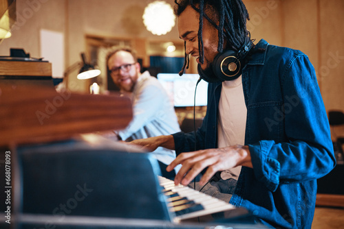 Smiling young musician playing keyboards during a recording studio session