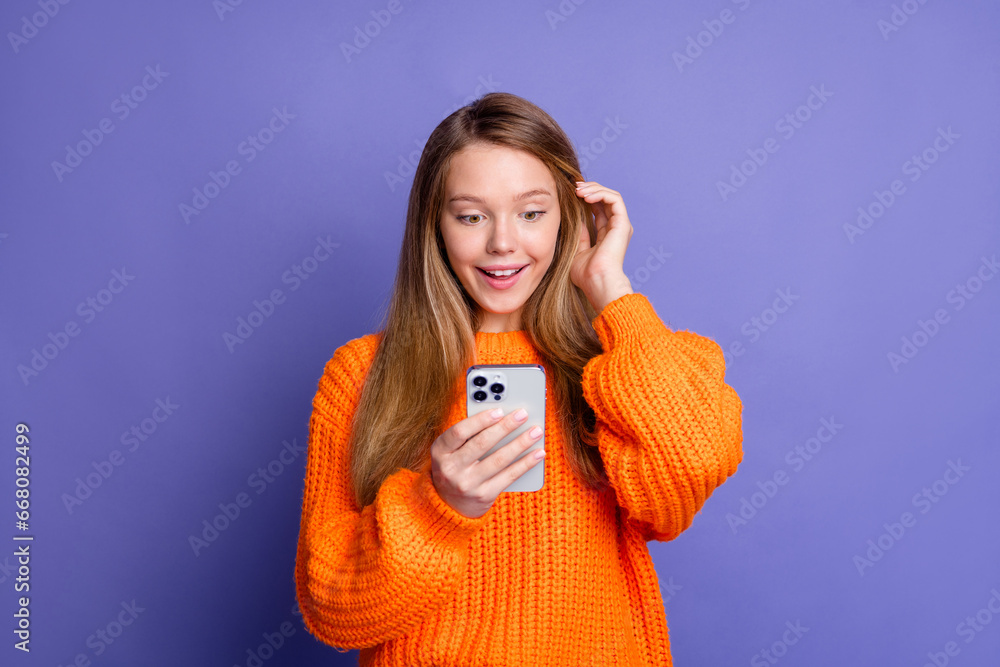 Photo of cute young girl touch her hair browsing smartphone excited spending time in internet isolated on over purple color background Photo of cute young girl touch her hair browsing smartphone excited spending time in internet isolated on over purple color background