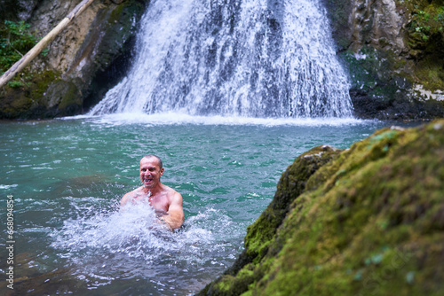 Fototapeta Naklejka Na Ścianę i Meble -  Strong man bathing in a waterfall