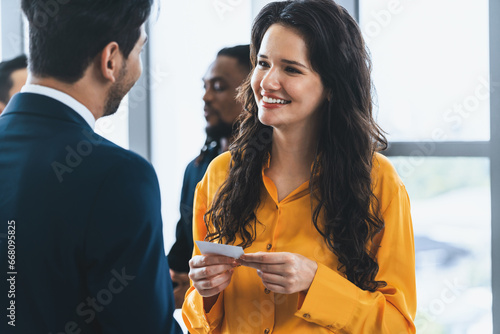 Successful businesswoman holding the name card during talking to manager about their cooperation. Female leader looking businessman during hold his name card admirably. Intellectual. photo