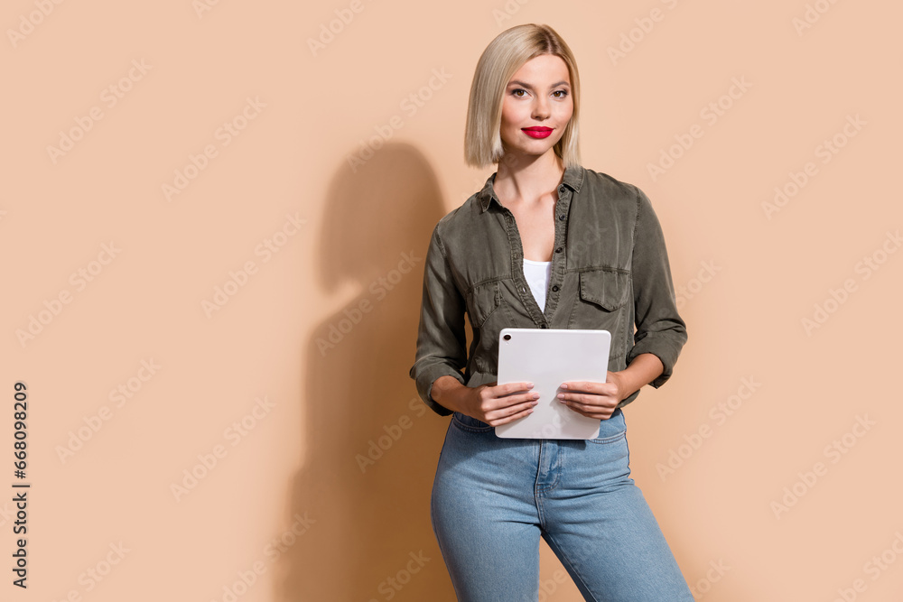 Photo of cheerful confident woman dressed khaki shirt texting modern device empty space isolated beige color background Photo of cheerful confident woman dressed khaki shirt texting modern device empty space isolated beige color background