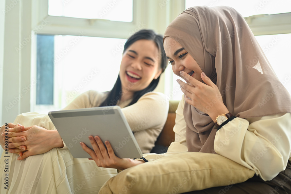 Two happy best friends laughing while watching funny videos on digital tablet Two happy best friends laughing while watching funny videos on digital tablet