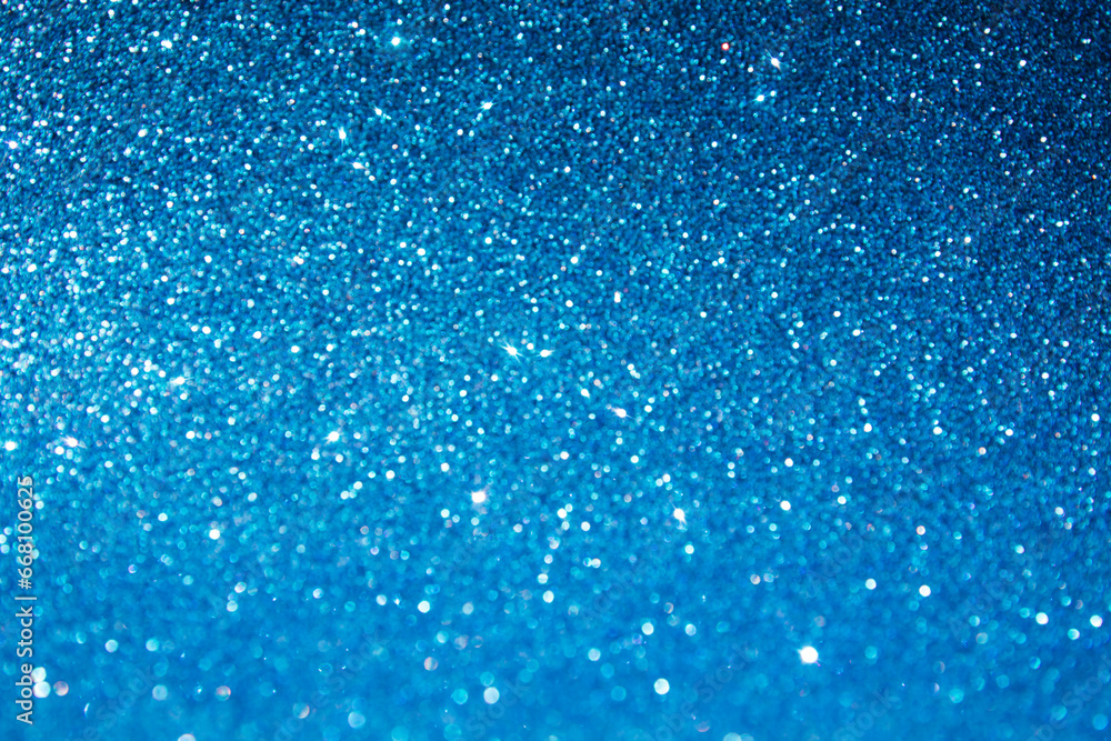 Obraz premium Shining sparkling blue blurred background for holiday design. Christmas abstract sparkles, selective focus