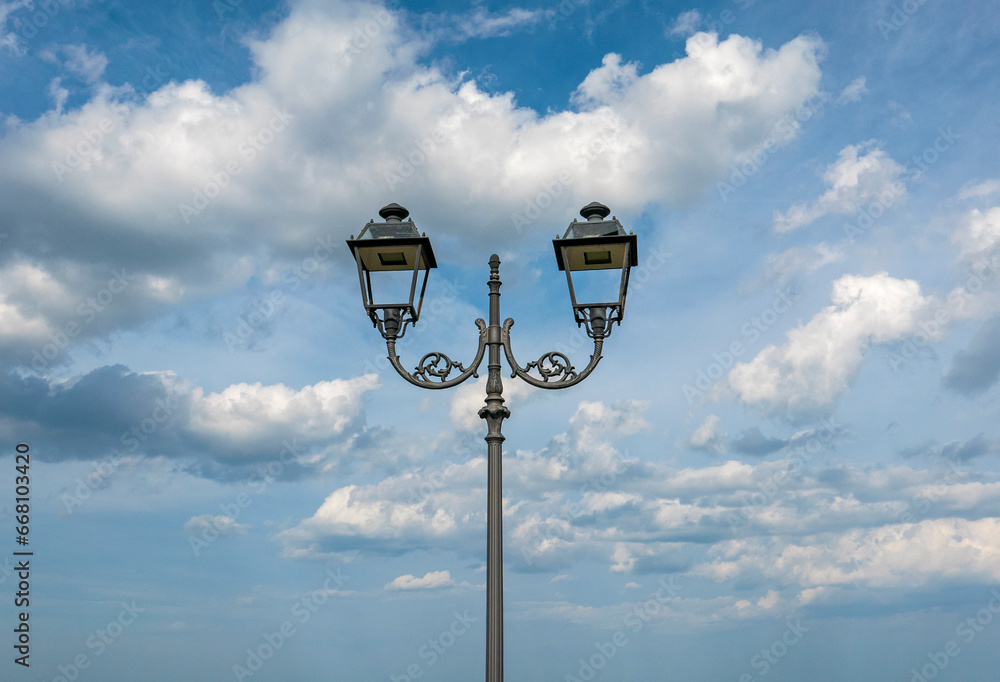 scenic view of decorative street lamp against sky clouds scenic view of decorative street lamp against sky clouds