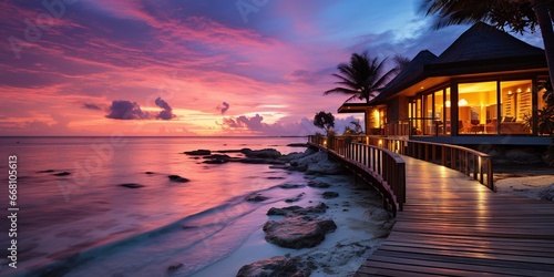 Amazing sunset panorama at Maldives. Luxury resort villas seascape with soft led lights under colorful sky. Beautiful twilight sky and colorful clouds. Beautiful beach background for vacation © Sanych