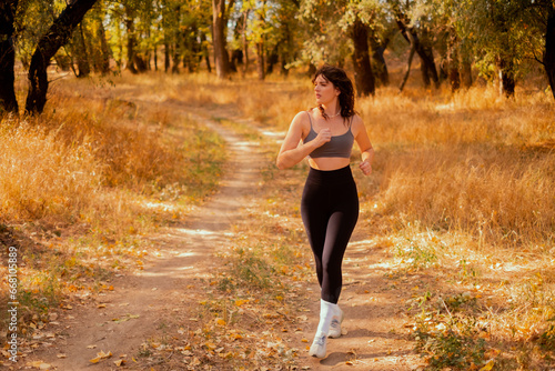 Woman running in the park on an autumn morning, healthy lifestyle concept, people doing sports outdoors, fresh air, drinking water, healthcare, authenticity, sense of balance and calm. © Svetlana Golovko