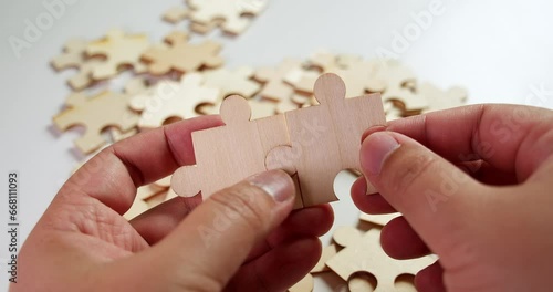 Jigsaw Puzzle pieces on the table then the lefthand and the righthand put two pieces together making them fit before laying on the table. photo
