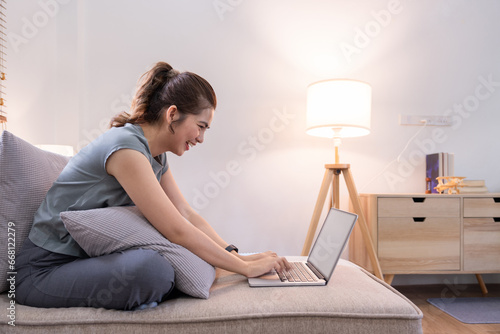 Photography Young woman asian using laptop pc computer on couch relax surfing the net at hom