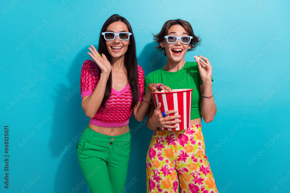 Portrait of two funny sisters 3d goggles first time excitement new barbie film shocked eat caramel popcorn isolated on blue color background Portrait of two funny sisters 3d goggles first time excitement new barbie film shocked eat caramel popcorn isolated on blue color background