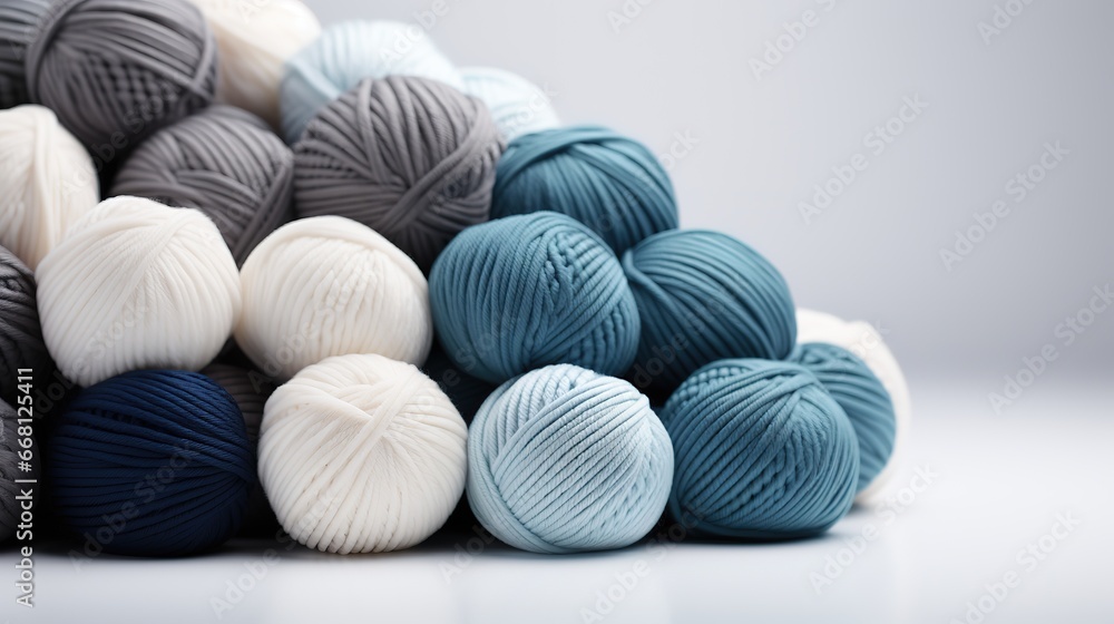 Fototapeta premium Blue, white and greya Balls of wool yarn lie on a whute background, hobby knitting