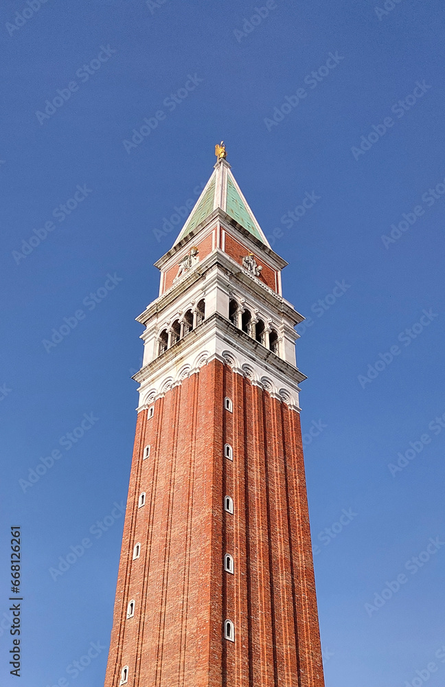 Piazza San Marco with top of Campanile di San Marco with golden angel on top at City of Venice on sunny summer day.