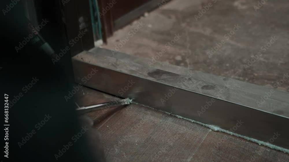 a master installs doors to an apartment in a house, gluing the slots of the platband with glue and foam a master installs doors to an apartment in a house, gluing the slots of the platband with glue and foam
