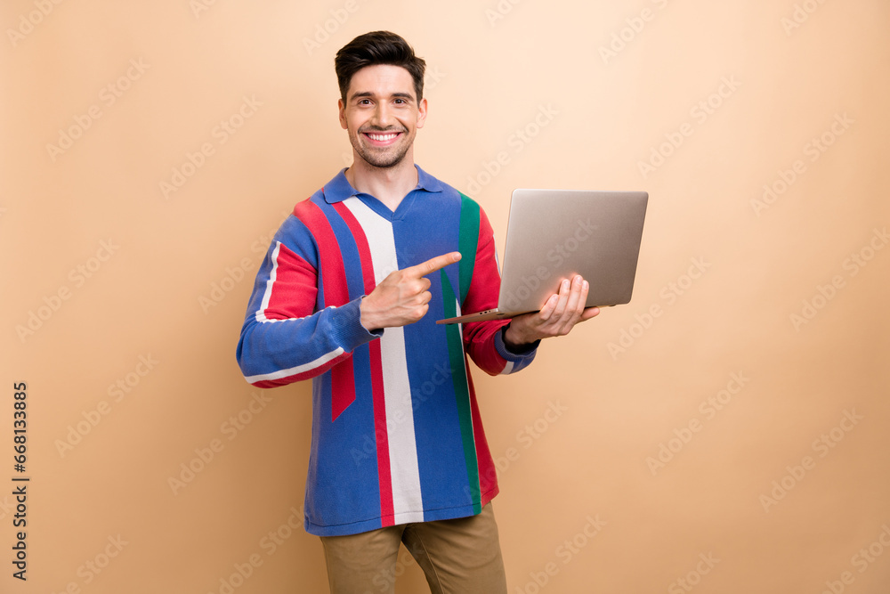 Portrait of cheerful person beaming smile direct finger wireless netbook isolated on beige color background Portrait of cheerful person beaming smile direct finger wireless netbook isolated on beige color background