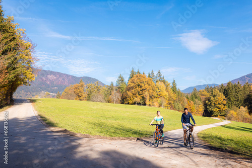 Cycling couple relaxing and enjoying a ride at the park in the autumn season. Recreation, leisure, and nature concepts.
