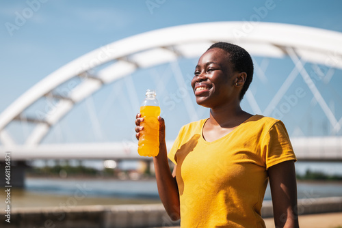 Woman drinking energy drink while exercise outdoor..	 photo