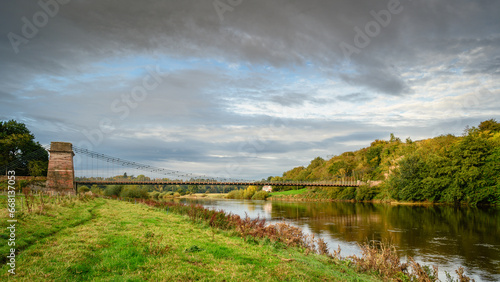 River Tweed flows below Union Chain Bridge, a suspension road bridge that spans the River Tweed between England and Scotland located four miles upstream of Berwick Upon Tweed photo
