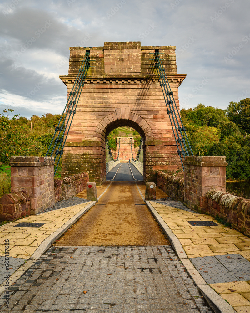 Obraz premium Portrait of entrance to Union Chain Bridge, a suspension road bridge that spans the River Tweed between England and Scotland located four miles upstream of Berwick Upon Tweed