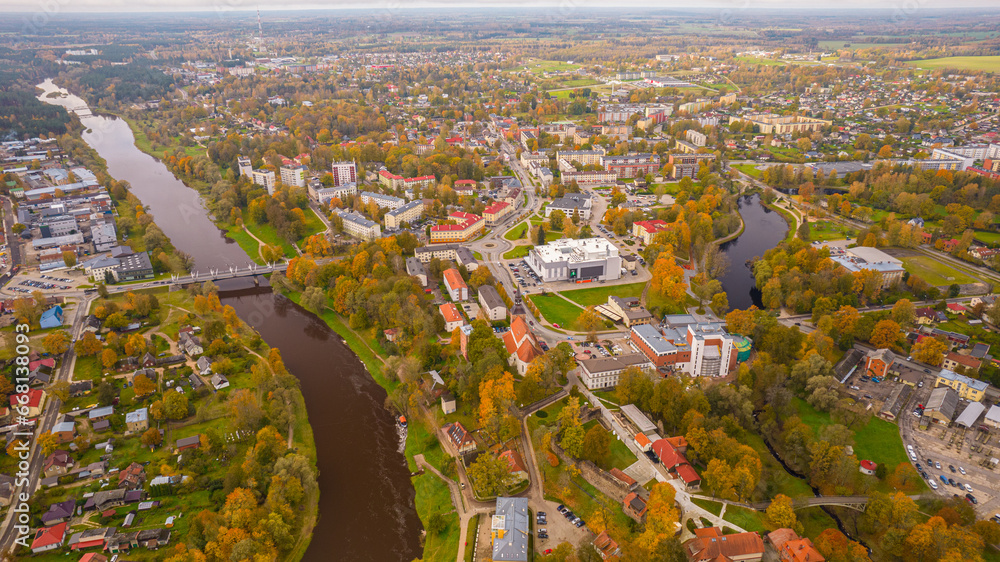 City of Valmiera from above in autumn. Panoramic Fall Landscape with Cityscape, Clouds, and Foliage. Cityscape with autumn foliage, flowers, and a tree in high angle view.