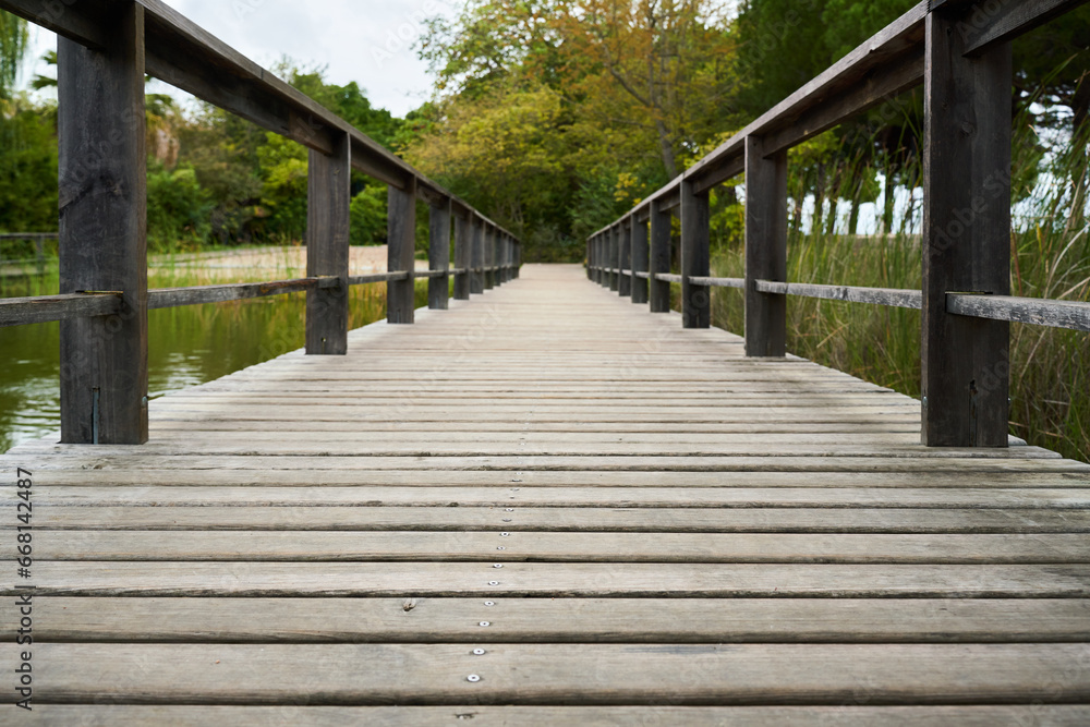 perspective view of an old wooden bridge with green vegetation blurred in the background