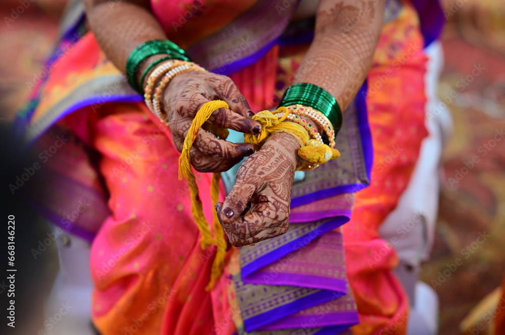Yellow Turmeric Thread on hand of bride. Hands of bride in hindu wedding. Saree and bracelets