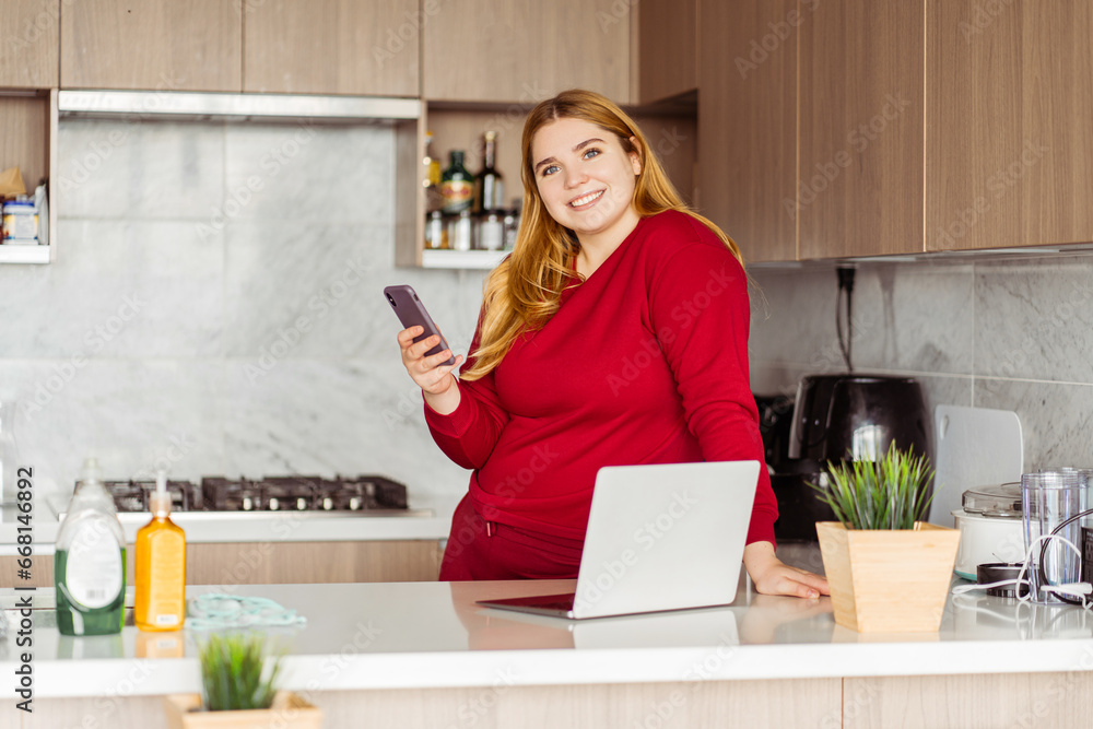 Portrait of body positive woman wearing red casual clothes holding mobile phone, using laptop Portrait of body positive woman wearing red casual clothes holding mobile phone, using laptop