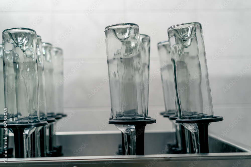 Naklejka premium Empty clean transparent glass wine bottles stand upside down and ready to be filled with drink at winery