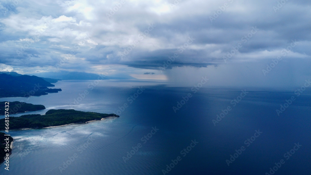 Aerial view of the strait between the islands and rain on the horizon. Rain and thunderclouds over the sea and tropical islands.