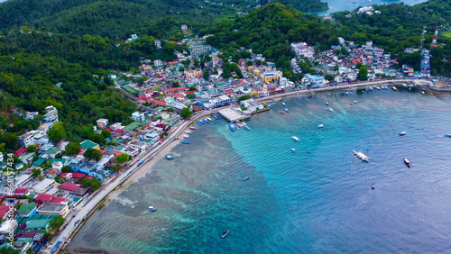 Aerial view of a small town on the shore of a lagoon on a tropical island. Small town, bay, lagoon, boats in the port. Sabang, Puerto Galera, Oriental Mindoro, Philippines. photo