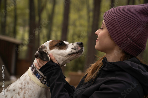 Outside a Glamping , The girl wearing a woolen cap plays with her dog in the middle of nature during winter.
