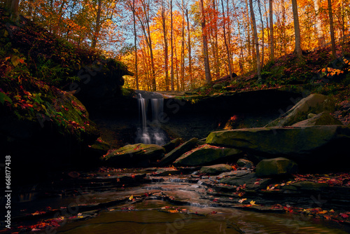 A Waterfall sits within a gorgeous, Autumn colored forest.  photo